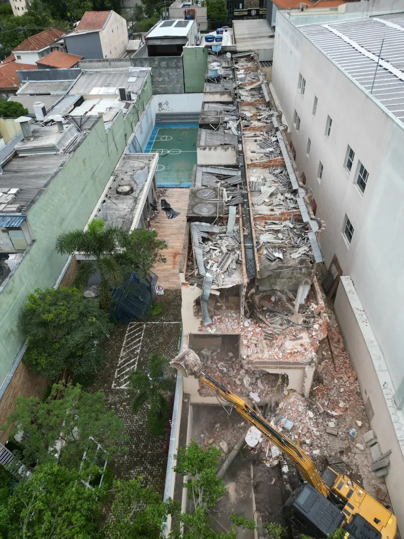Escavadeira da R5 em demolição mecanizada entre prédios