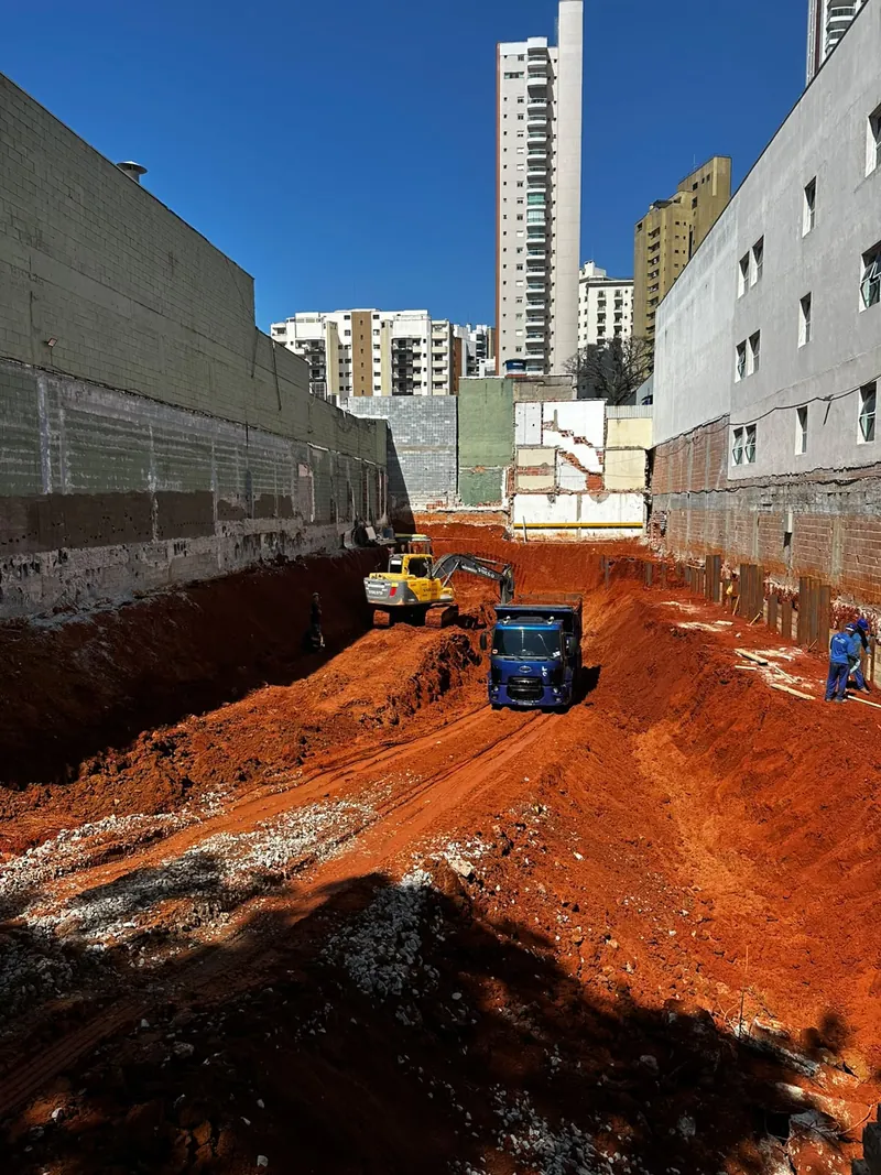 Escavadeira carregando caminhão em escavação de subsolo